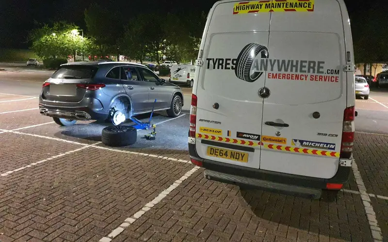 A Tyres Anywhere van at a night call-out, with a customer's car on a jack in a car park