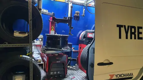 Inside a mobile tyre fitting van with a tyre changer, wheel balancer and new tyres