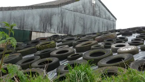 Old tyres weighing down silage sheeting outside a farm barn