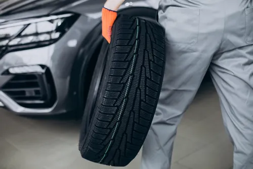 Mechanic holding a new tyre for a car