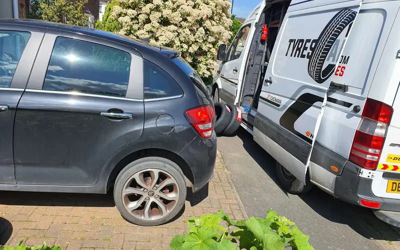 A Tyres Anywhere van beside a car having its tyres replaced on a driveway