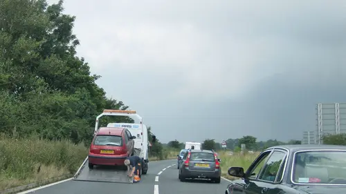 A broken-down car being loaded onto a recovery truck at the roadside