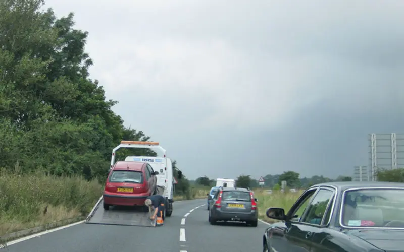 A broken-down car being loaded onto a recovery truck at the roadside