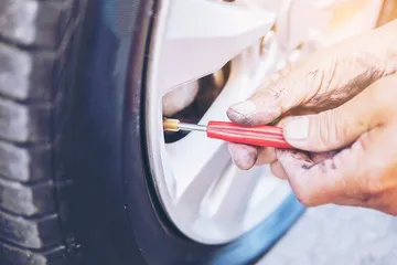 Guy putting air in a tyre using emergency repair kit