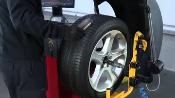 Mechanic using a wheel balancing machine